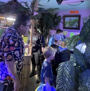 Children looking at fish tank in an aquarium shop with an older gentleman speaking to them about the fish