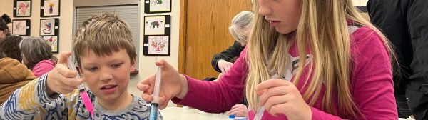 Young boy and girl using a syringe to drop paint into a test tube