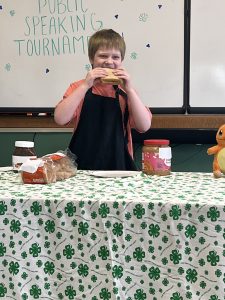 4-H youth biting into a sandwich with a smile