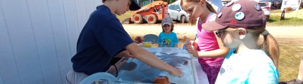 Youth gathered around the 4-H Touch Tank exhibit at the Blue Hill Fair, observing the sea creatures