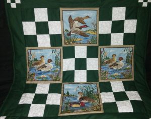Image of a green and duck print quilt being raffled by the Lock Stock and Barrel 4-H Club