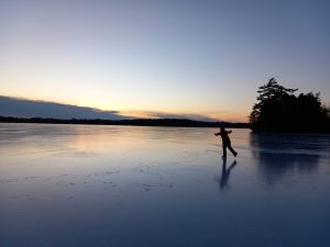 Photo of a iceskater on a pond backlit by the sunset