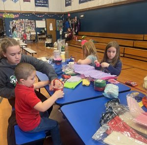 Youth sitting at a table surrounded by craft supplies