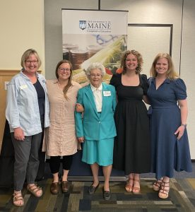 5 women smiling with a UMaine Foundation sign