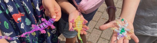 Youth holding bead lizard keychains of various colors