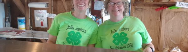 Two smiling Jolly Juniors volunteers in the food booth