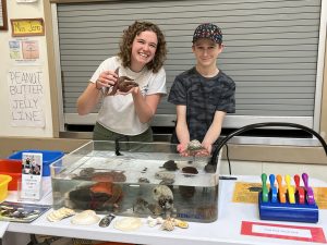 Staff member Leah and 4-H youth Wyatt holding sea creatures during a touch tank. 