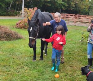 Youth leading a horse with a volunteer following behind, pointing where to turn