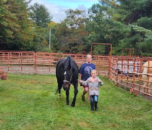 Youth leading a horse with a volunteer following behind