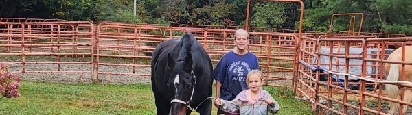 Youth leading a horse with a volunteer following behind