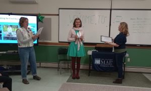 Staff members Leah and Andrea presenting Margaret Mae with an award plaque.