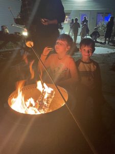 Youth roasting and eating smores around a campfire