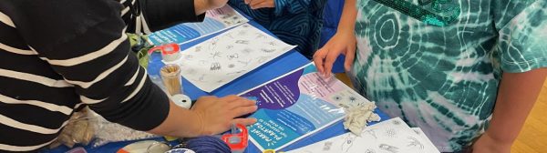 4-H Staff explaining a workshop activity to two youth listening intently.