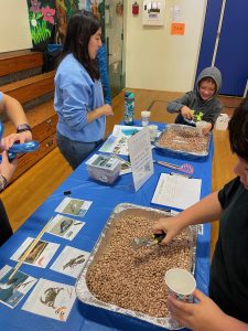 Youth using tongs to pick up beans at the microplastics workshop