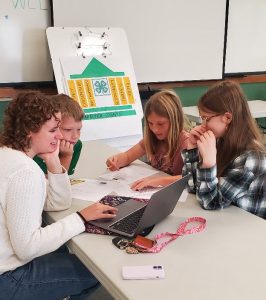 Leah and three youth gathered around a computer