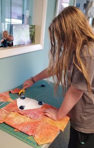 4-H Youth using a rotary cutter to cut out a triangular pattern