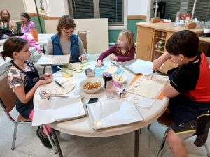 Youth gathered around a table cutting pie dough into shapes