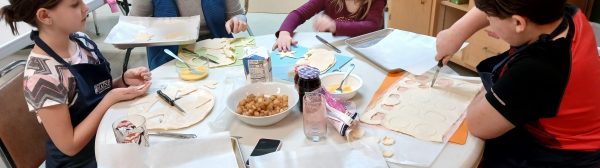 Youth gathered around a table cutting pie dough into shapes