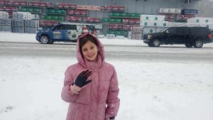 Youth smiling and waving at the camera on a snowy day. Wreaths Across America vans are in the background