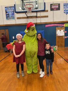 Three youth posing with someone dressed as the grinch