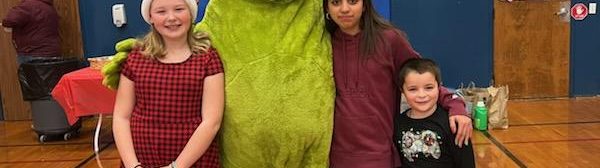 Three youth posing with someone dressed as the grinch