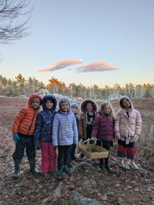 group of youth dressed for the cold smiling at the camera with a sunset background outside