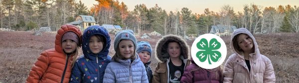 group of youth dressed for the cold smiling at the camera with a sunset background outside