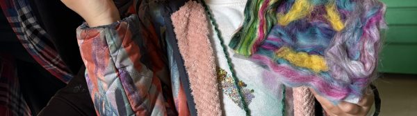 Youth smiling at the camera and holding up two needle felting projects.