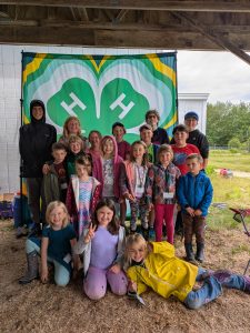 Youth gathered at 4-H June Jamboree in front of a giant 4-H clover display