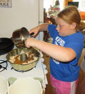Youth pouring batter in a pan to bake a dessert.
