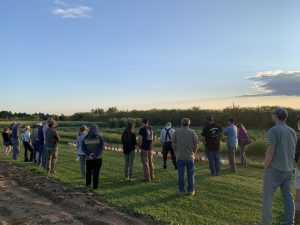 People standing in a pumpkin field during a fall twilight meeting.