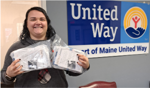 woman holding packages of pajamas in front of a United Way sign