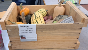 A wooden crate filled with various squash and potatoes