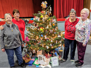 Four Extension Homemakers members from Franklin County gathered around a Christmas tree used for an auction fundraiser