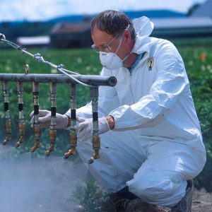 man with face mask working on pesticide spray unit