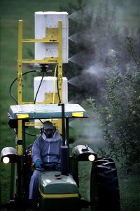 man wearing respirator driving tractor spraying pesticide