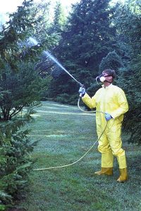 man spraying pesticide wearing respirator