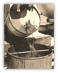 A drum of insecticide being mixed/loaded into a metal bucket