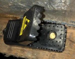 A black mousetrap, set and baited with cheese.