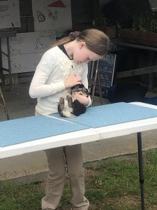 Girl holding a rabbit that is laying on a table
