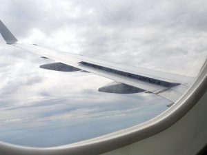 photo of an airplane wing and clouds taken though a passenger window