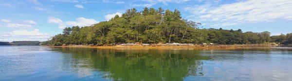 island in water with dramatic clouds on sunny day