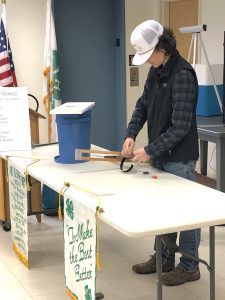 Young man behind a table demonstrating the use of an ice fishing trap