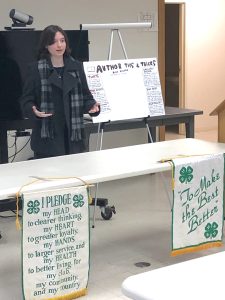 4-H youth speaking behind a table at public speaking tournament