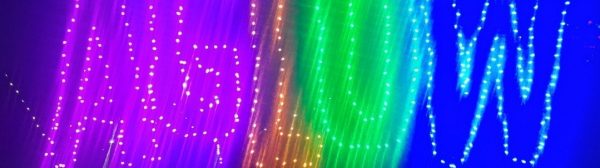 blurred image of letters spelling AGLOW traced in multi-colored lights