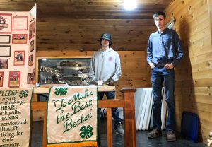 2 young people speaking from a stage with 4-H flags in foreground