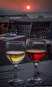 two glasses of wine on a table outside overlooking a sunset in the distance