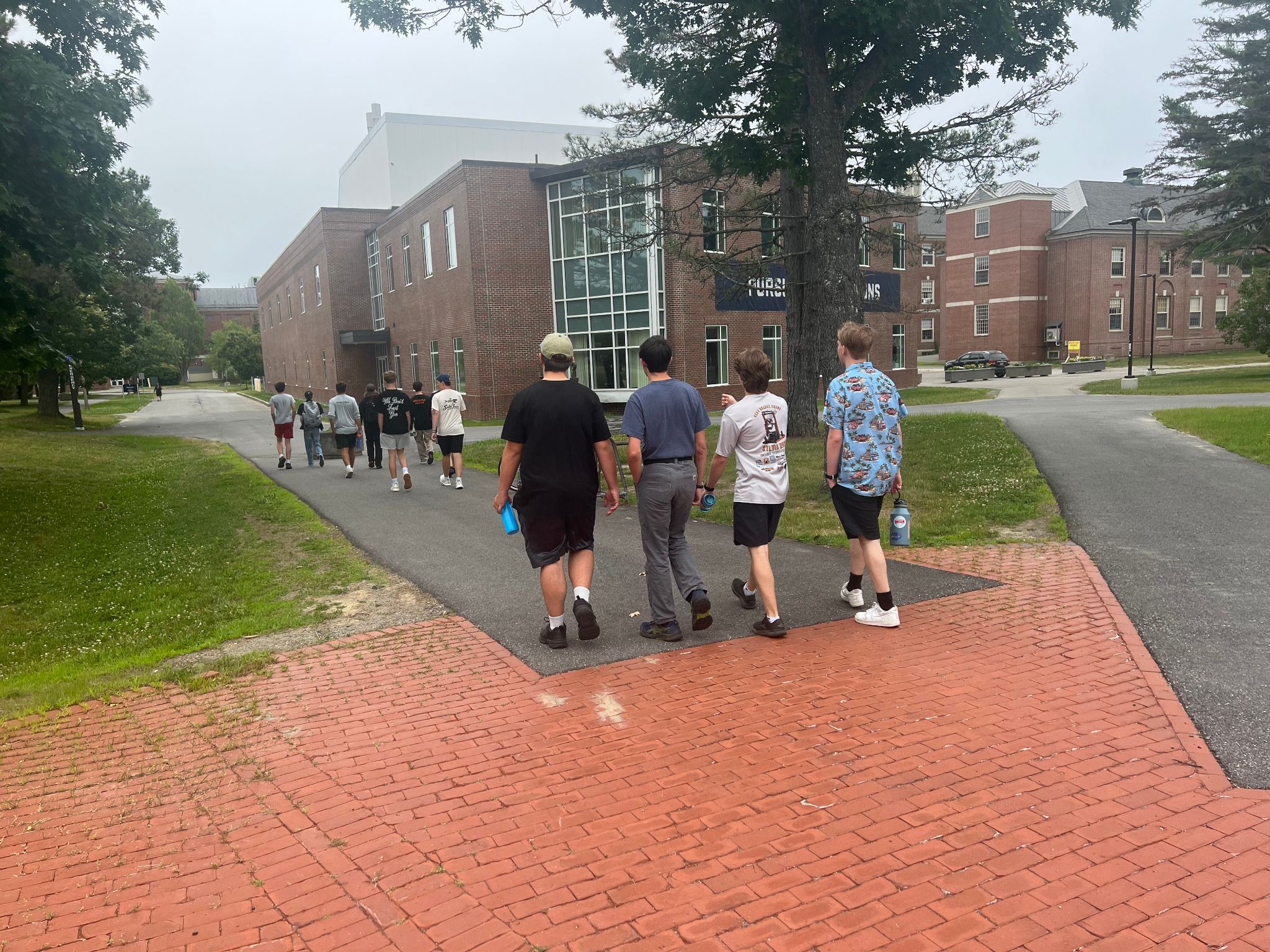 students walking on sidewalk outside of the building that houses the Advanced Manufacturing Center on the University of Maine campus