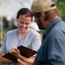 woman using a clipboard working with a farmer
