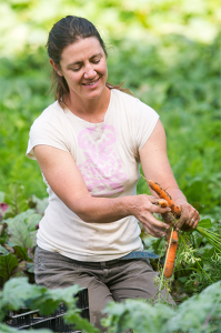 a woman in a garden with carrots out of the ground